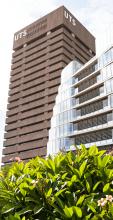Tall brown building with UTS sign and a glassed building beside it